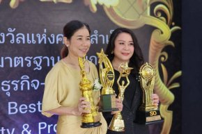 Two women holding multiple trophies at the Quality Awards ceremony, celebrating their achievements.