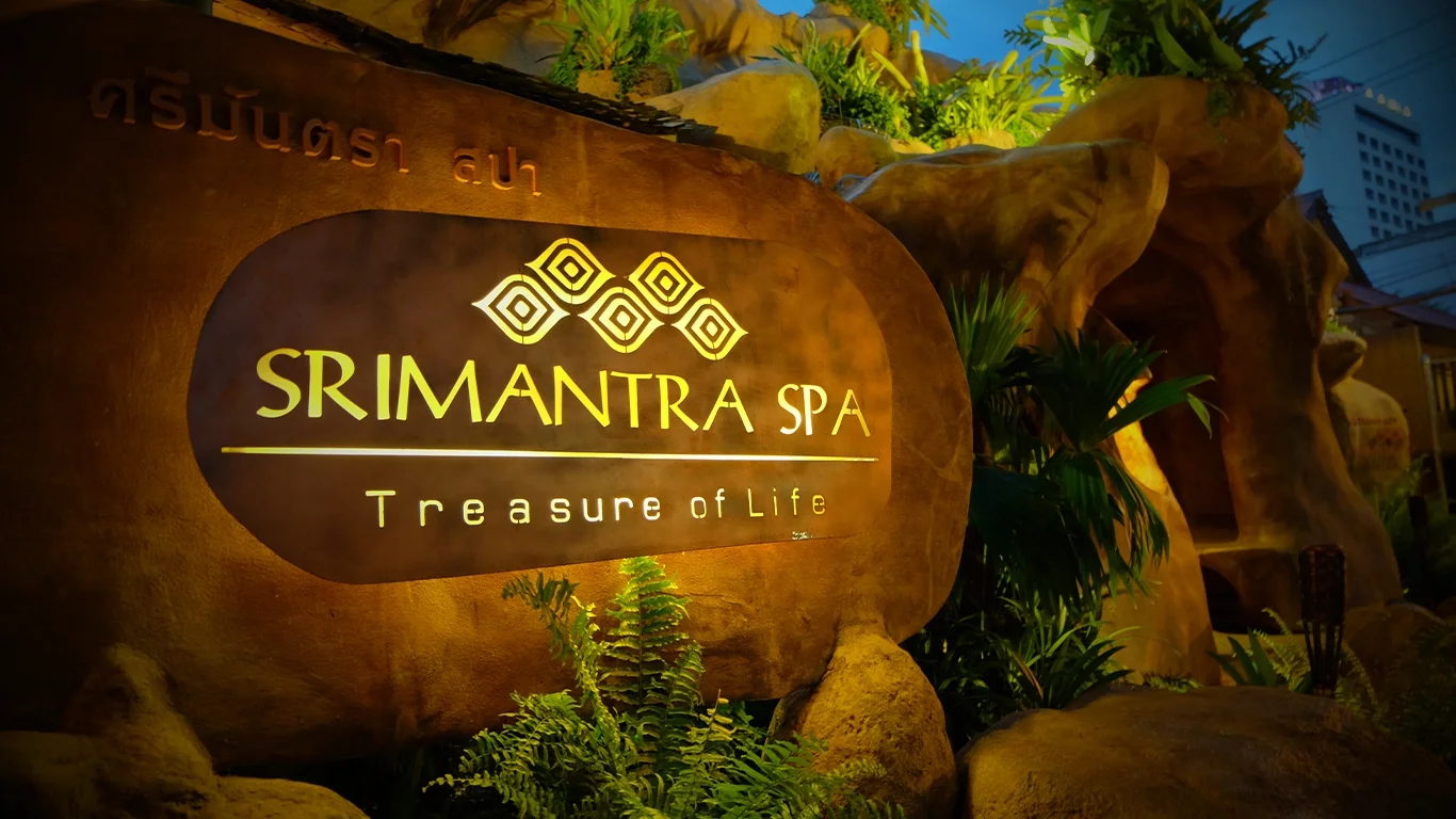 Srimantra Spa - Treasure of Life entrance sign, featuring a golden logo, natural rock, and lush green plants.