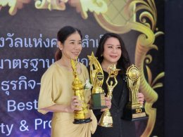 Two women holding multiple trophies at the Quality Awards ceremony, celebrating their achievements.