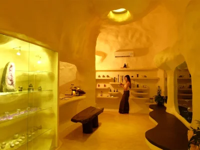 Inside a Chiang Mai spa with a cave-like design and warm golden lighting, a woman stands among wellness products and decor.