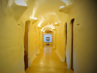 A cave-like spa hallway in Chiang Mai, with light-colored walls and warm lighting, leading to treatment rooms.
