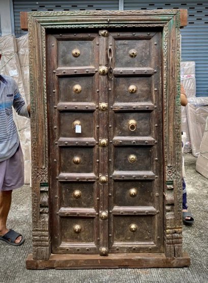 ประตูบ้านไม้สีเข้มแต่งหมุดทองเหลืองสวยงาม