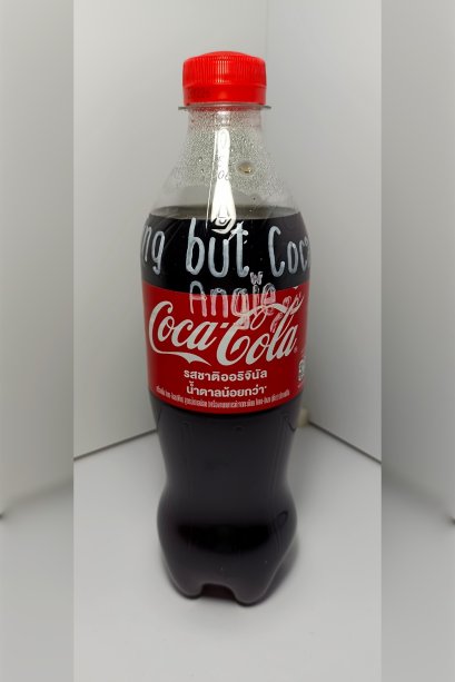 A bottle of Coca-Cola (Original taste Less sugar / A Thai label) 510 ml. which has My Slogan with My Signature