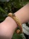 Antique gold cuff bangle featuring intricate lotus bud terminals with hand-chased petals, set with natural rubies and emeralds, showcasing traditional Thai royal goldsmithing techniques
