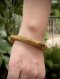 Antique gold cuff bangle featuring intricate lotus bud terminals with hand-chased petals, set with natural rubies and emeralds, showcasing traditional Thai royal goldsmithing techniques