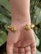 Antique gold cuff bangle featuring intricate lotus bud terminals with hand-chased petals, set with natural rubies and emeralds, showcasing traditional Thai royal goldsmithing techniques